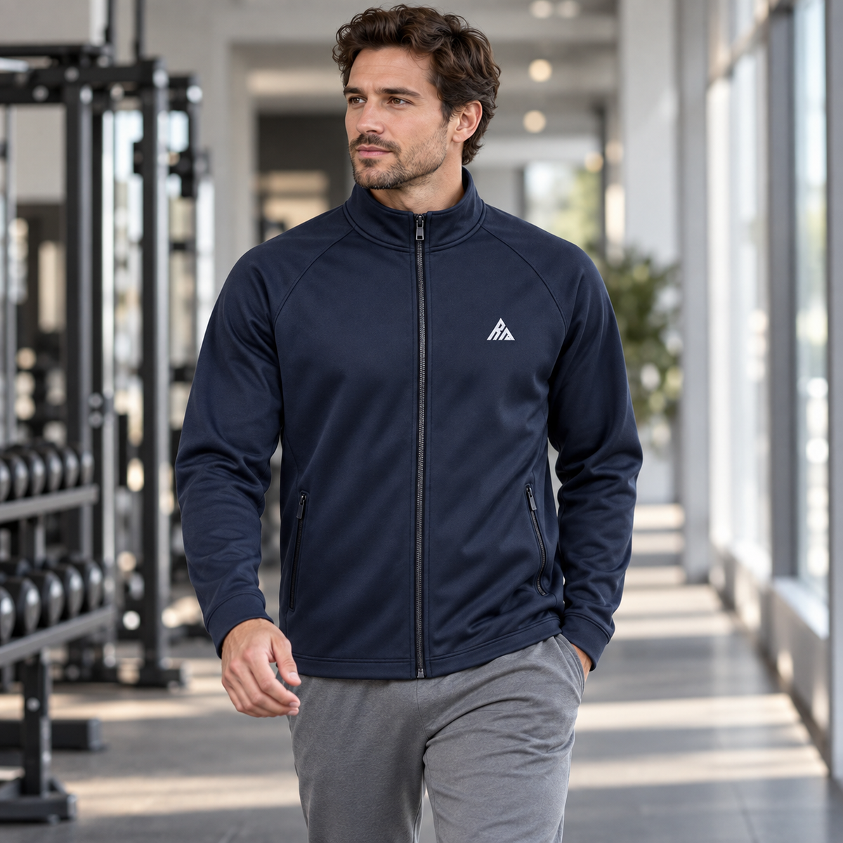 Man wearing the Real Marks minimal track jacket in navy in a modern gym