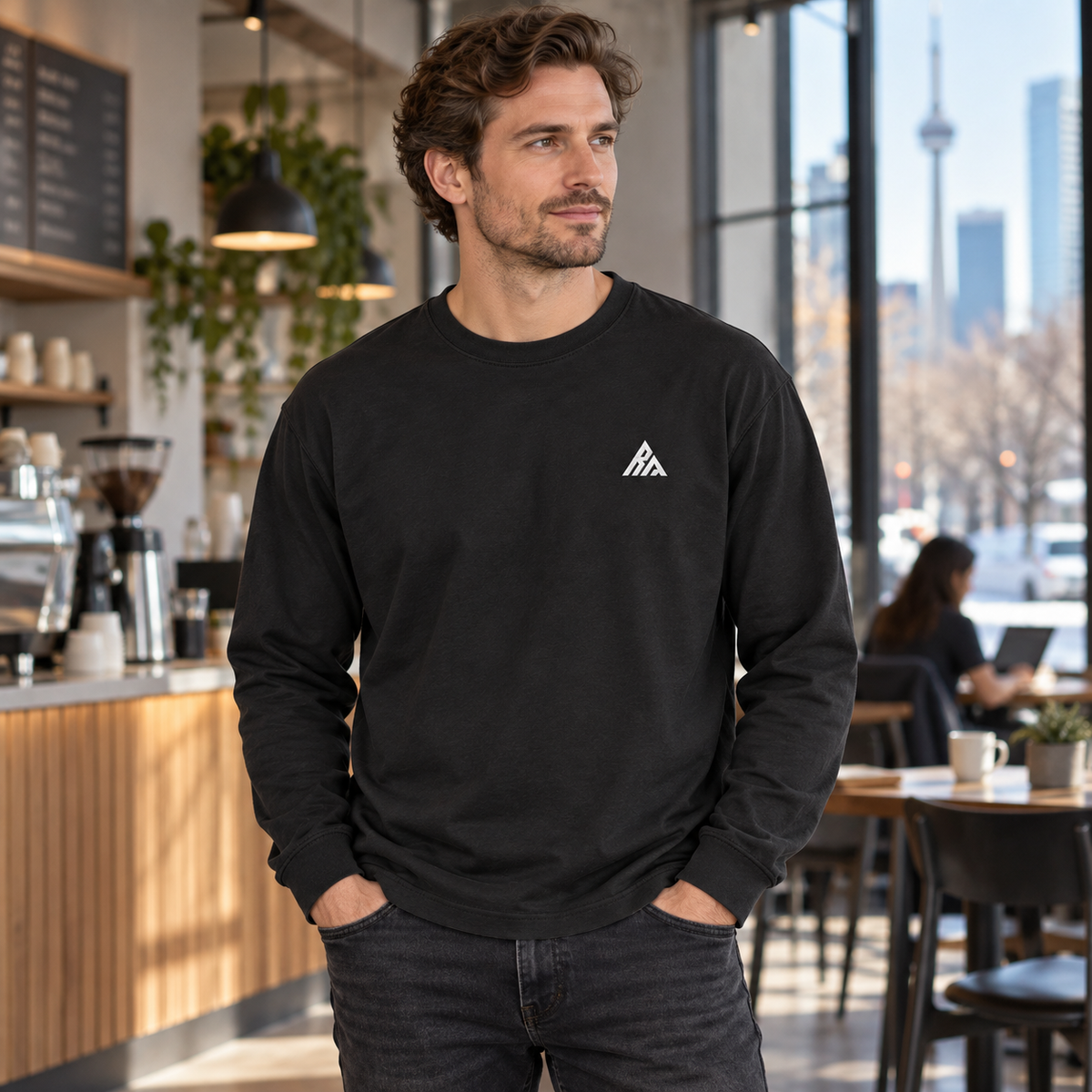 Man wearing the Real Marks relaxed long-sleeve T-shirt in black in a city café