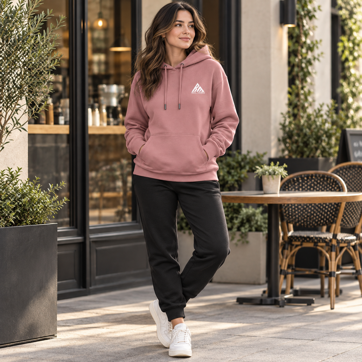 Woman wearing the rose Real Marks everyday pullover hoodie near a cafe